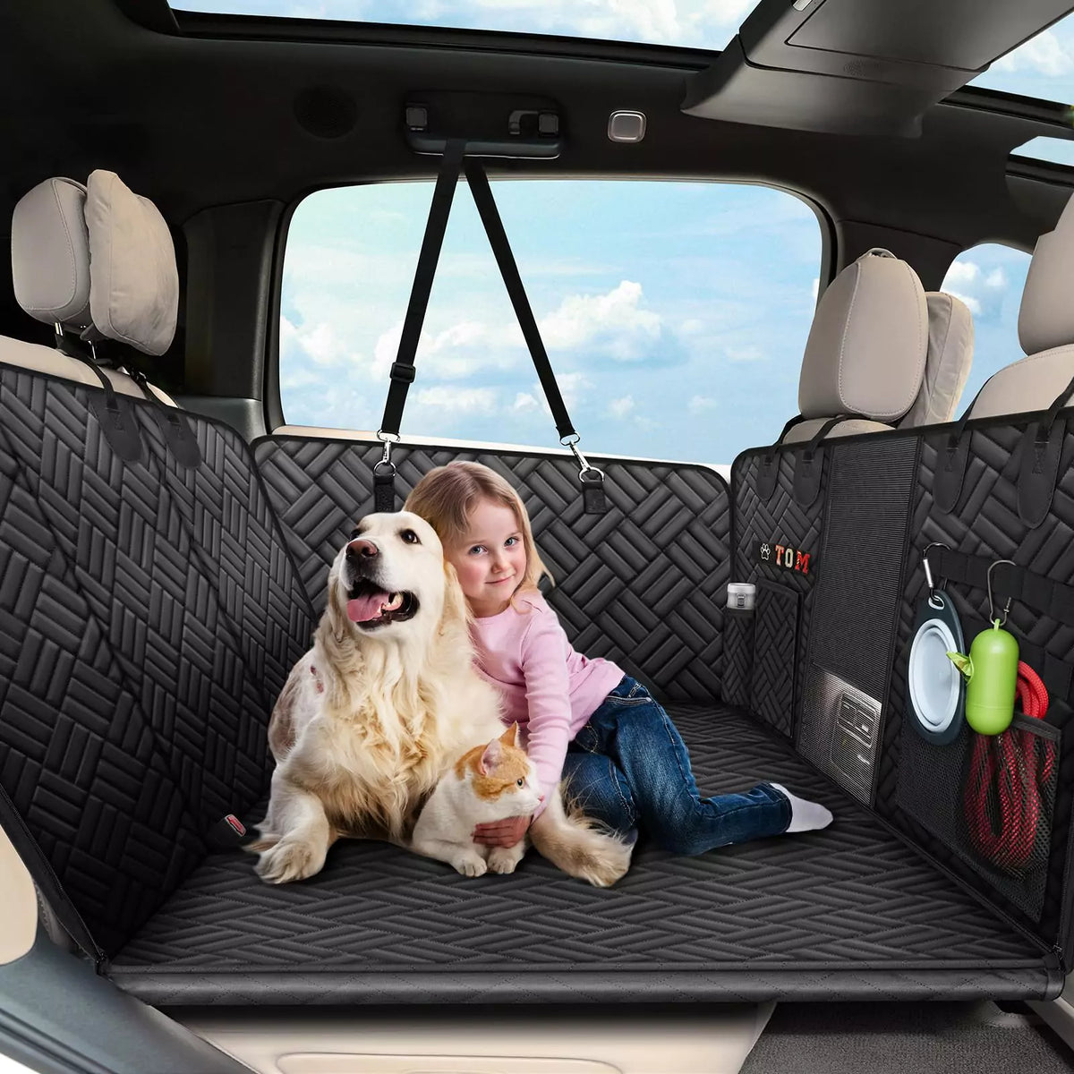 A dog and a kid lies on a black car back and seat pet cover